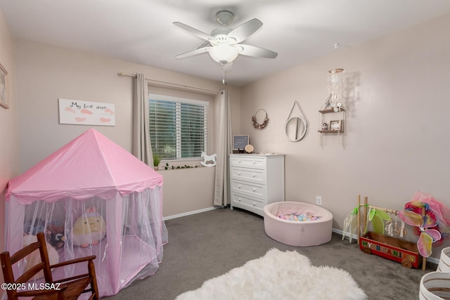 game room featuring a ceiling fan, dark colored carpet, and baseboards