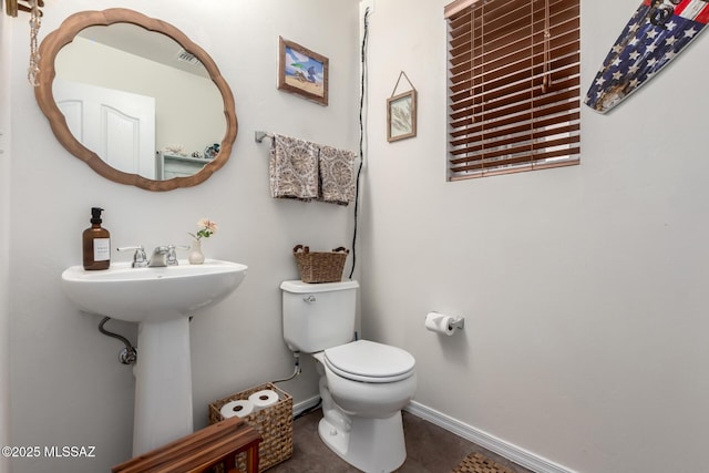 half bathroom with toilet, tile patterned flooring, and baseboards