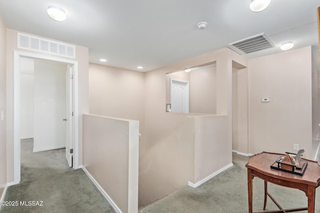 corridor with light colored carpet, visible vents, and an upstairs landing