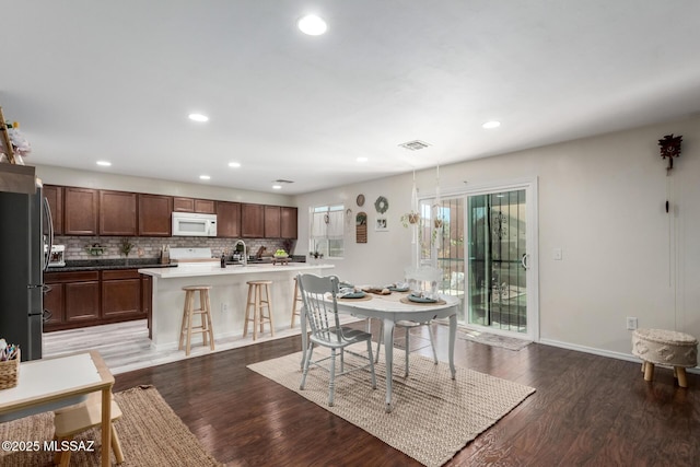 dining space with dark wood-type flooring, visible vents, and recessed lighting