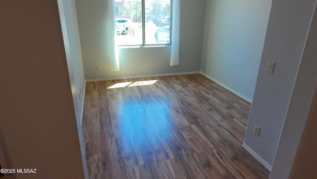 empty room with baseboards and wood finished floors