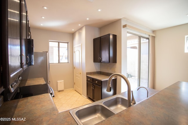 kitchen featuring dark brown cabinetry, a sink, recessed lighting, and electric stove
