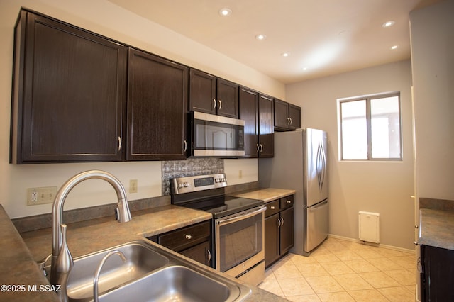 kitchen with a sink, decorative backsplash, dark brown cabinetry, appliances with stainless steel finishes, and recessed lighting