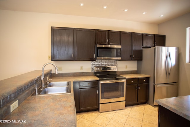 kitchen with stainless steel appliances, a sink, light tile patterned flooring, dark brown cabinets, and recessed lighting