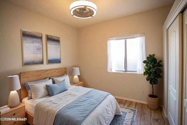 bedroom with wood finished floors, a closet, and baseboards