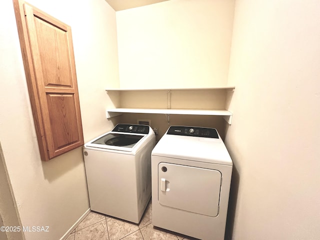 clothes washing area with washer and dryer, light tile patterned flooring, and laundry area