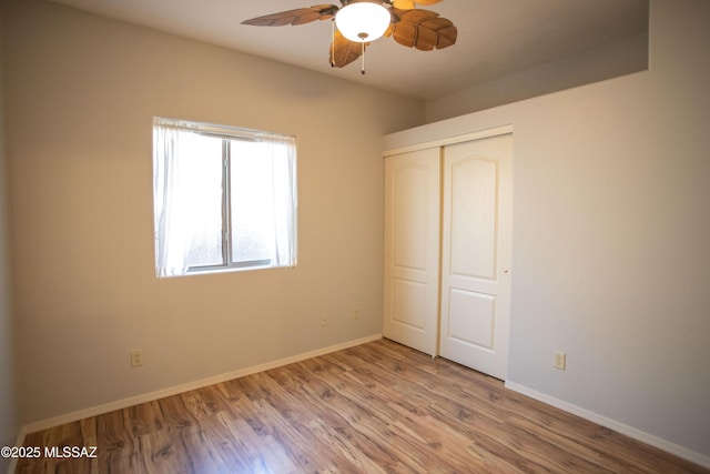 unfurnished bedroom featuring baseboards, a ceiling fan, wood finished floors, and a closet