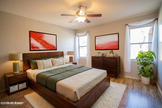 bedroom with ceiling fan, baseboards, and light wood finished floors