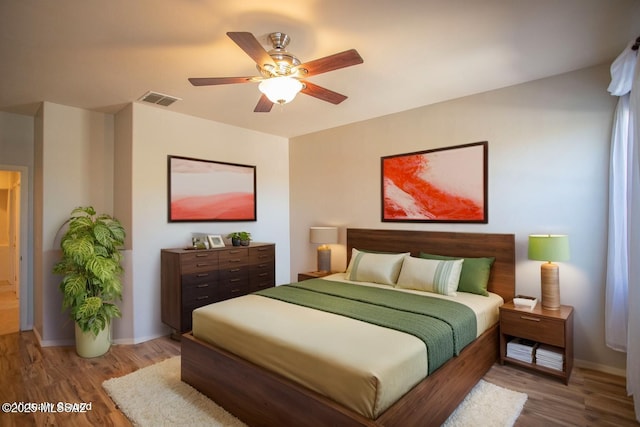 bedroom with baseboards, wood finished floors, and visible vents