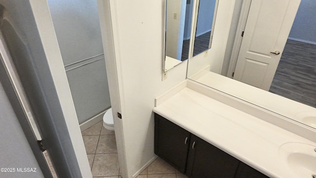 bathroom featuring tile patterned flooring, baseboards, toilet, and vanity