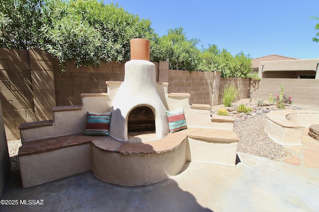 view of patio with exterior fireplace and fence