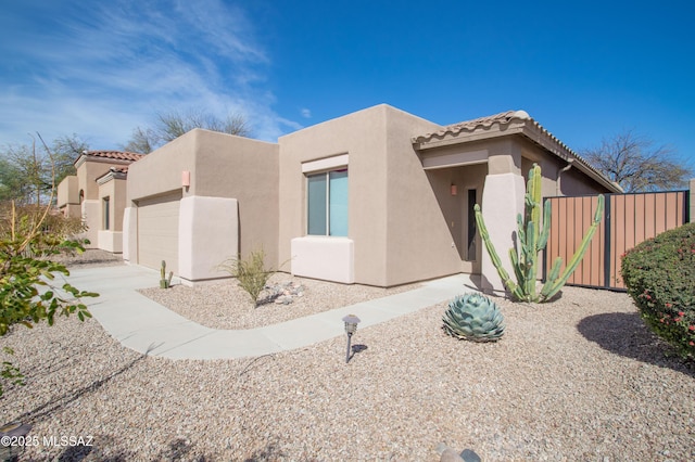 southwest-style home with a garage, a tile roof, stucco siding, and fence