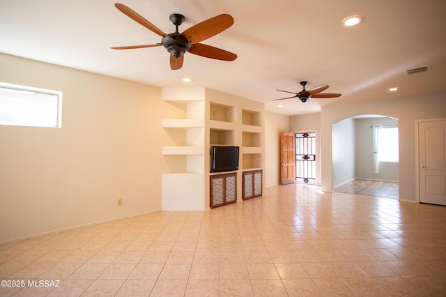 unfurnished living room with arched walkways, visible vents, recessed lighting, a ceiling fan, and light tile patterned floors