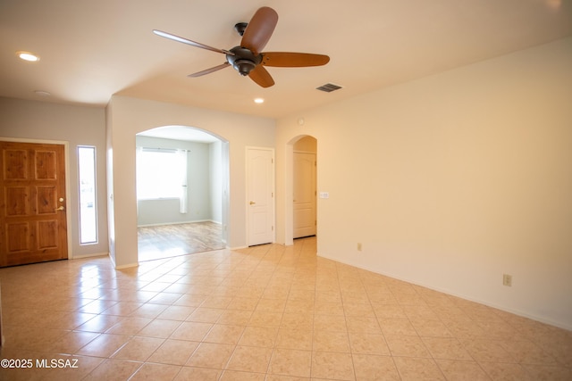 empty room with ceiling fan, arched walkways, baseboards, visible vents, and recessed lighting