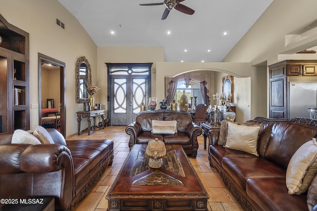 living area with visible vents, arched walkways, ceiling fan, french doors, and high vaulted ceiling