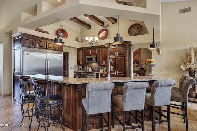 kitchen with a breakfast bar, a peninsula, a high ceiling, and stainless steel appliances