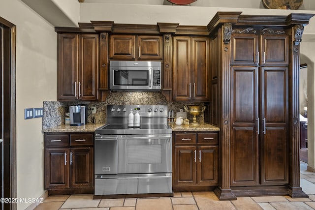 kitchen featuring stainless steel appliances, dark brown cabinetry, backsplash, and light stone counters