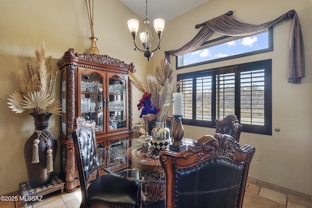 dining area featuring an inviting chandelier, baseboards, and vaulted ceiling