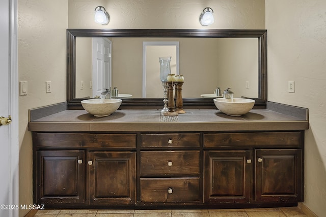 full bath with a textured wall, double vanity, and a sink