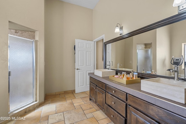 bathroom with a stall shower, stone tile floors, and a sink