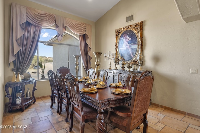 dining area featuring visible vents, lofted ceiling, stone tile flooring, and baseboards