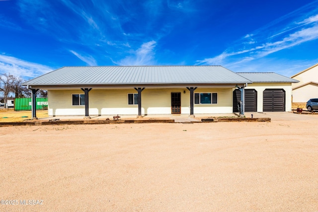 ranch-style house with metal roof, concrete driveway, and a garage