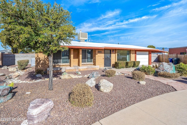 ranch-style house with brick siding, an attached garage, and fence