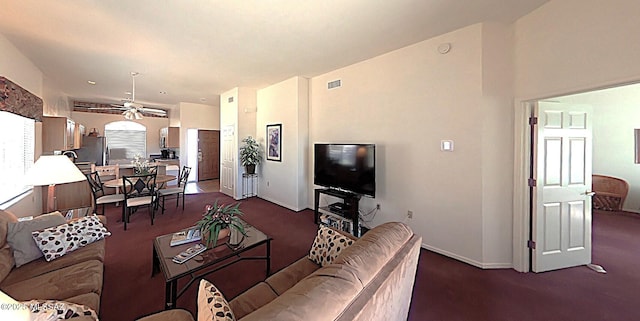 living area featuring dark colored carpet, visible vents, and baseboards