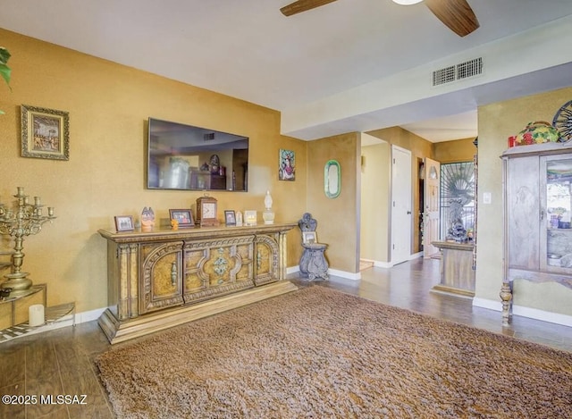 living area featuring baseboards, ceiling fan, visible vents, and wood finished floors