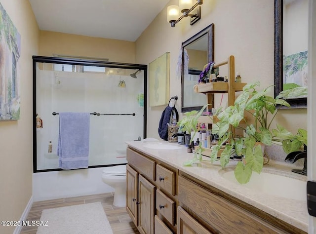 full bathroom featuring enclosed tub / shower combo, toilet, wood finish floors, and vanity