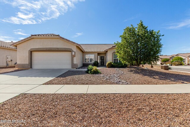 mediterranean / spanish-style house with a garage, concrete driveway, a tiled roof, and stucco siding