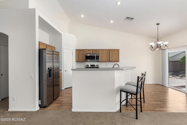 kitchen featuring brown cabinets, decorative light fixtures, light countertops, visible vents, and appliances with stainless steel finishes