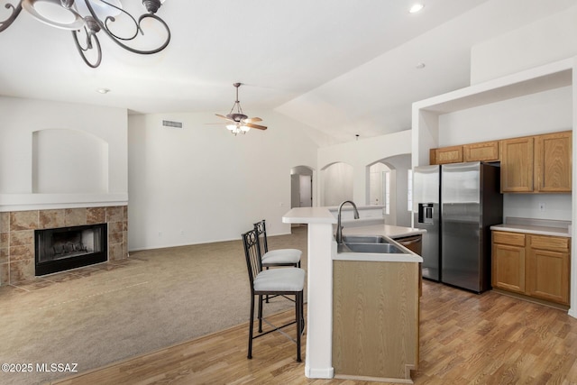 kitchen with an island with sink, a kitchen breakfast bar, open floor plan, light countertops, and stainless steel refrigerator with ice dispenser