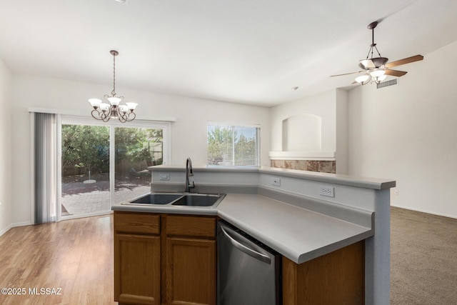 kitchen with brown cabinets, light wood-style flooring, stainless steel dishwasher, a sink, and an island with sink