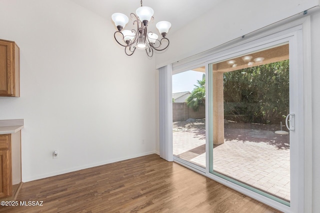 interior space featuring baseboards, a chandelier, and wood finished floors
