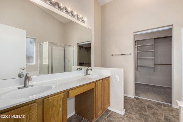 bathroom with double vanity, a stall shower, a walk in closet, and a sink