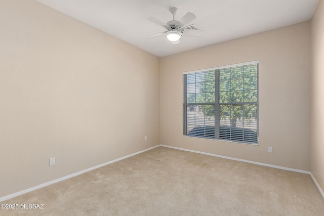 spare room with light colored carpet, ceiling fan, and baseboards