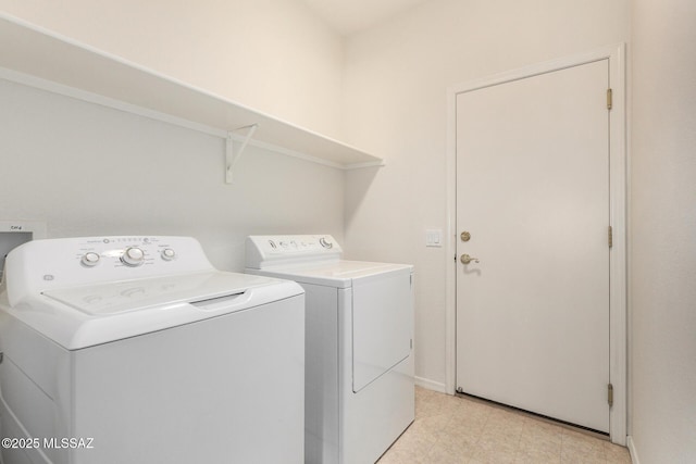clothes washing area with laundry area, light floors, washing machine and clothes dryer, and baseboards