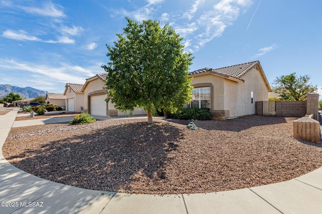 view of front of property featuring a mountain view, a garage, fence, a tiled roof, and stucco siding