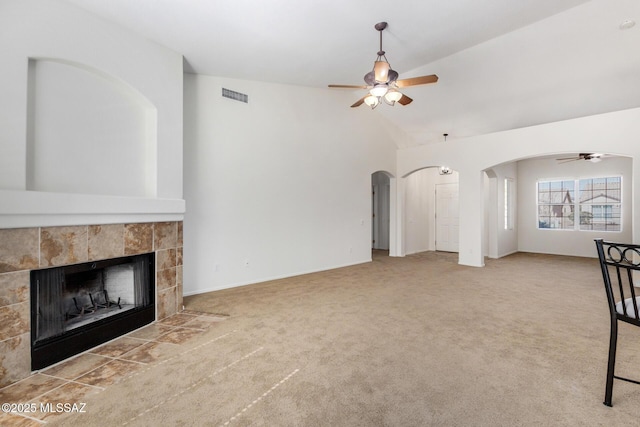 unfurnished living room with carpet floors, a ceiling fan, visible vents, and a tiled fireplace