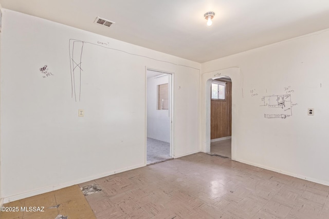 unfurnished room featuring arched walkways, baseboards, visible vents, and light floors