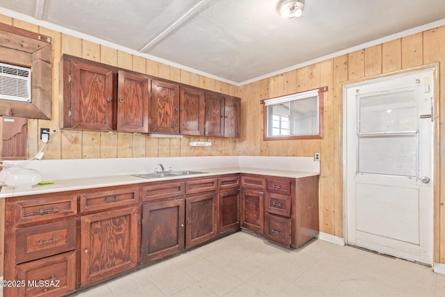 kitchen with light countertops, a sink, and wood walls