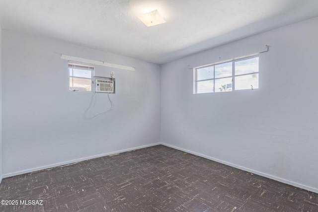 spare room with dark floors, plenty of natural light, and baseboards