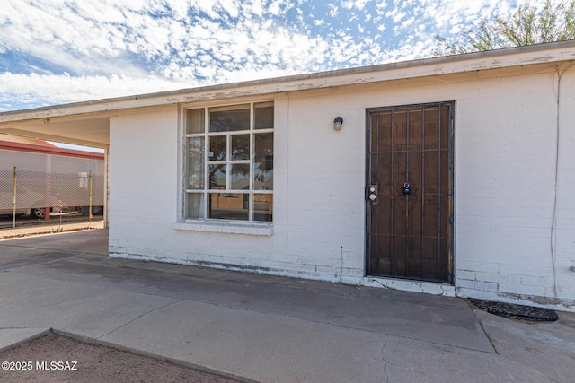 doorway to property with a carport and brick siding