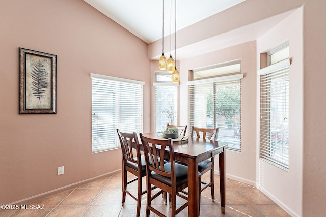 tiled dining space with vaulted ceiling and baseboards