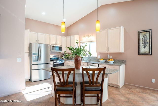 kitchen featuring stainless steel appliances, a kitchen island, hanging light fixtures, light stone countertops, and a kitchen bar