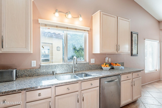 kitchen featuring light stone counters, a sink, stainless steel dishwasher, and light tile patterned floors