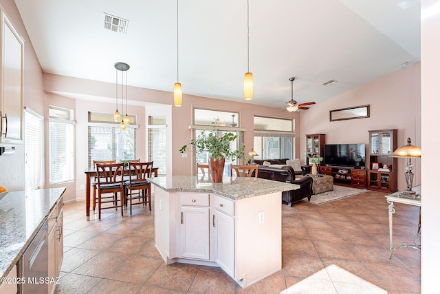 kitchen featuring visible vents, white cabinets, a kitchen island, decorative light fixtures, and light stone countertops