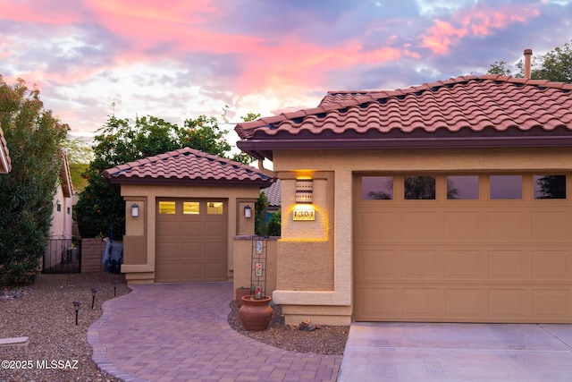 mediterranean / spanish house featuring a garage, decorative driveway, and stucco siding