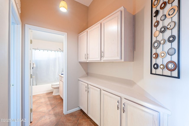 hallway featuring baseboards and dark tile patterned flooring